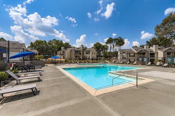 A swimming pool surrounded by sun loungers and apartment buildings